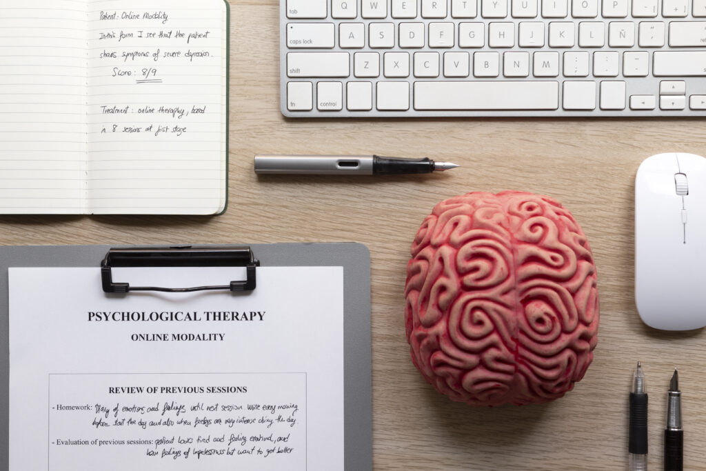 Keyboard, brain replica, and psychological therapy documents on the table.