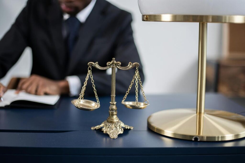 A person writing on a blue table with scale of justice