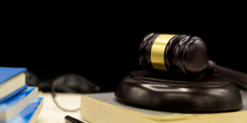 Close-up shot of books, a pen, eyeglasses, and a gavel placed on top of a book