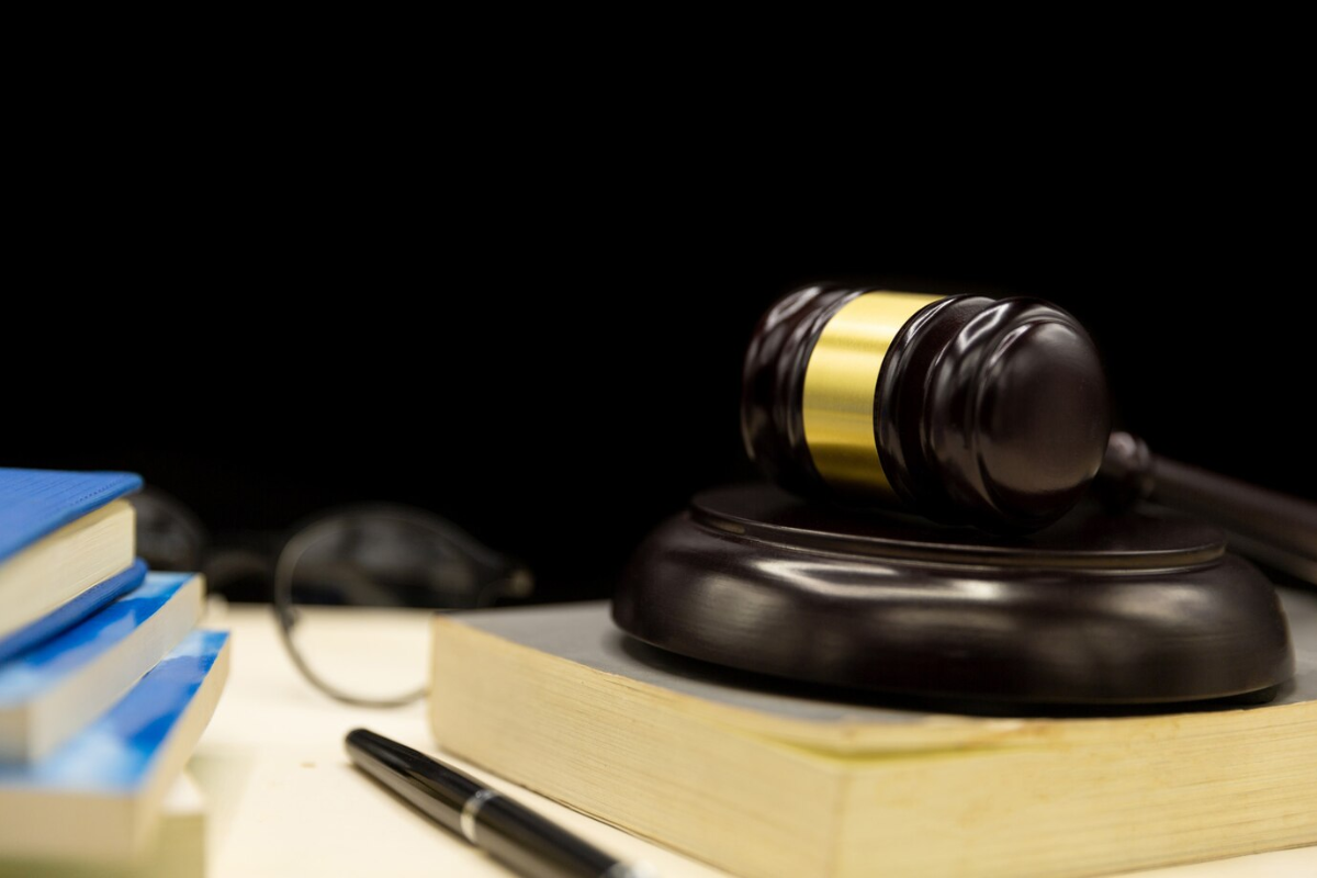 Close-up shot of books, a pen, eyeglasses, and a gavel placed on top of a book