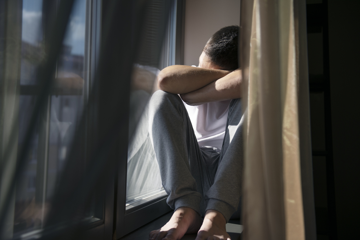 A man sitting beside the window, suffering from a mental disorder.