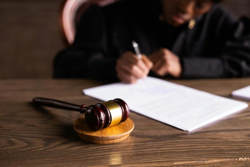 A person writing on a document with a gavel on the table