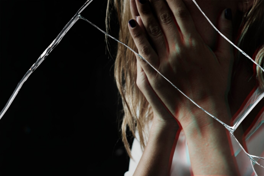 A woman, the victim, crying near shattered glass
